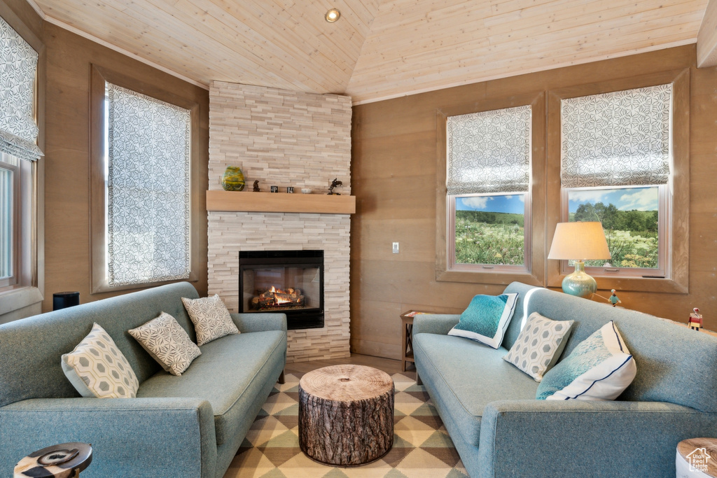 Living area featuring wood ceiling, plenty of natural light, vaulted ceiling, and a stone fireplace