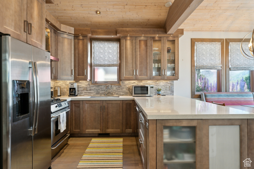 Kitchen with appliances with stainless steel finishes, a sink, a peninsula, wood finished floors, and wood ceiling