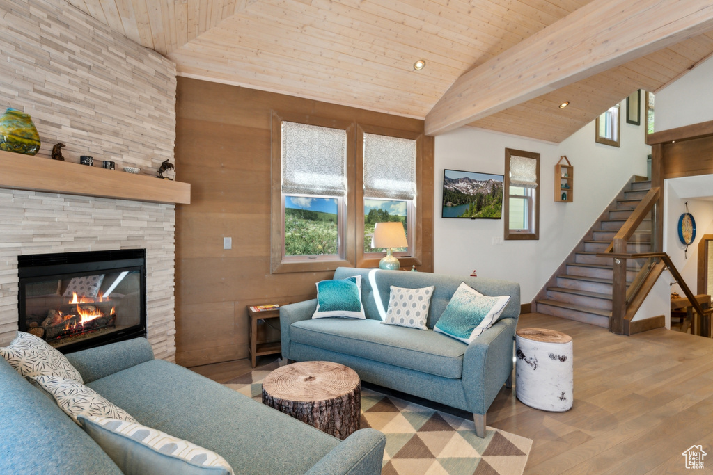 Living room with wooden ceiling, wood finished floors, stairway, a fireplace, and high vaulted ceiling