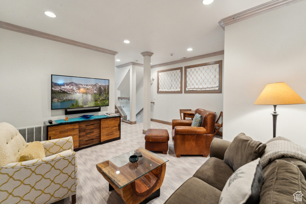 Living area with crown molding, recessed lighting, decorative columns, stairs, and light colored carpet