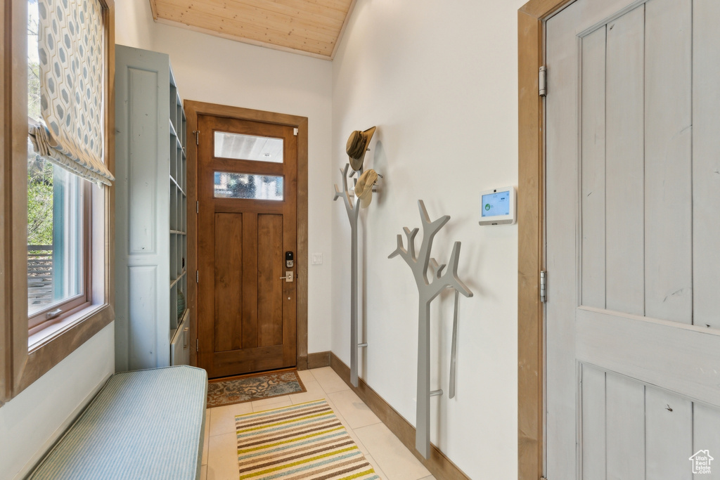 Foyer with light tile patterned flooring, baseboards, and wooden ceiling