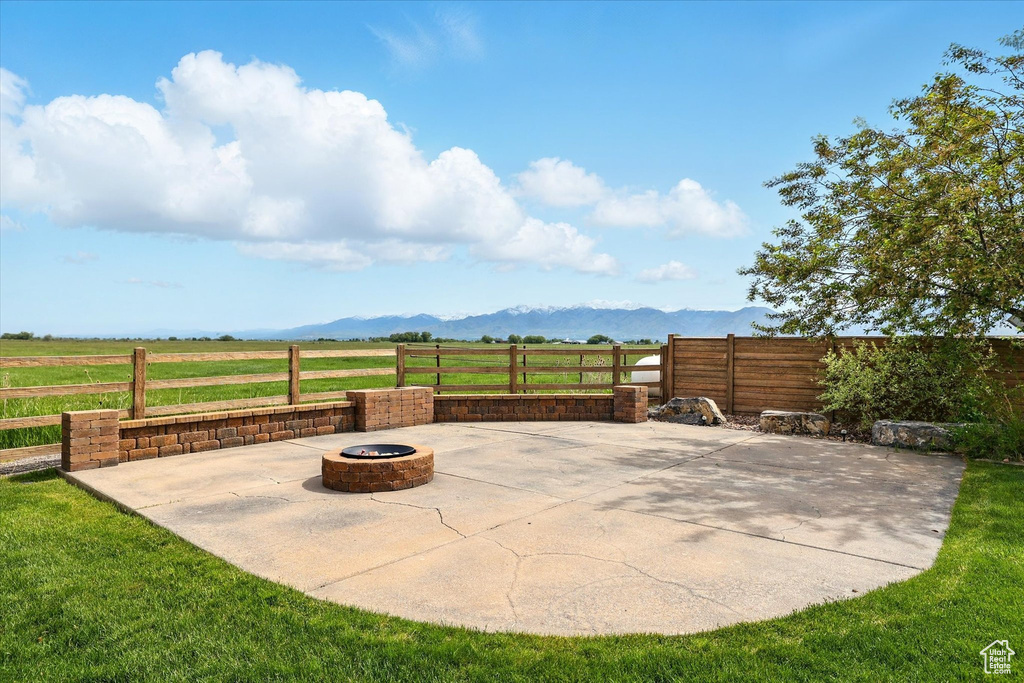 View of patio / terrace featuring an outdoor fire pit, a mountain view, and a view of rural / pastoral area