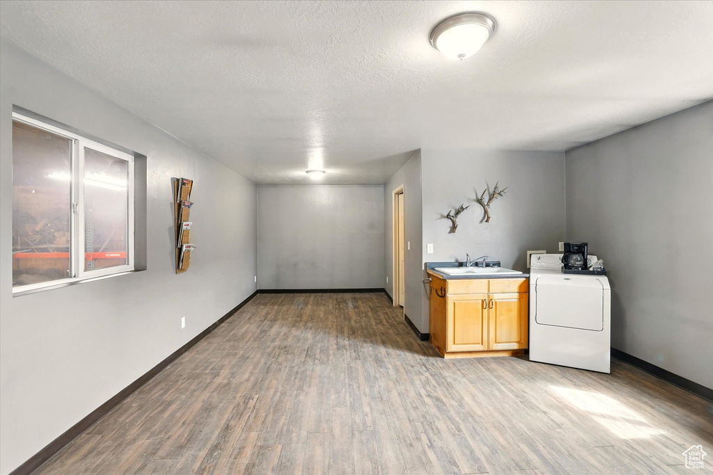 Basement with washer / clothes dryer, light wood-style floors, a sink, and baseboards