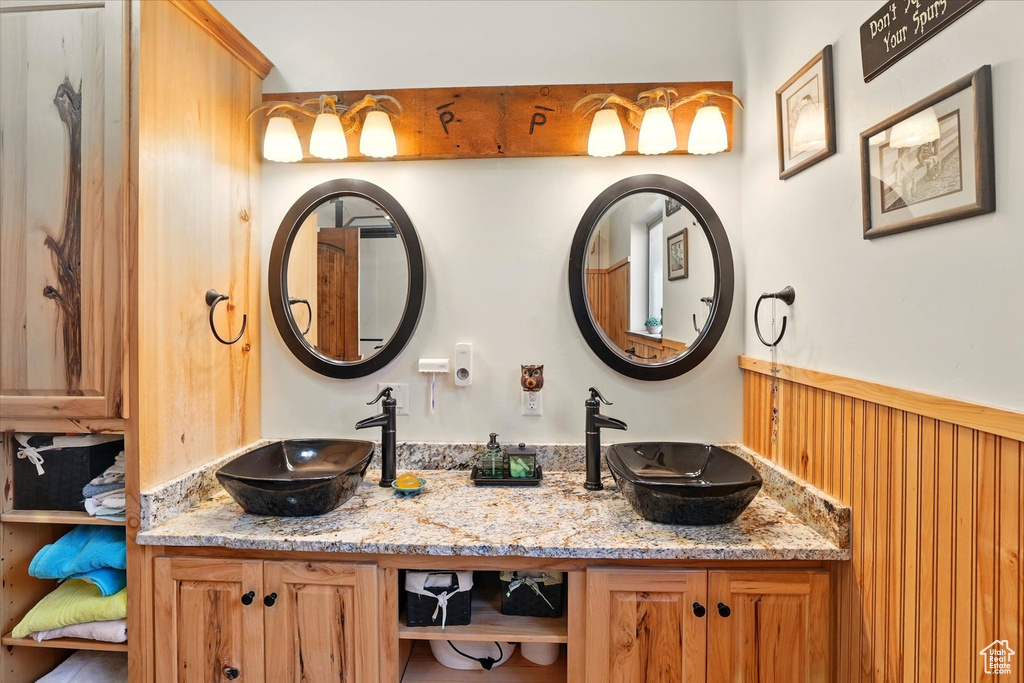 Full bath with double vanity and a wainscoted wall