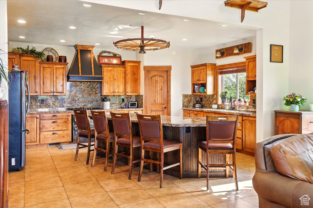 Kitchen featuring premium range hood, freestanding refrigerator, recessed lighting, tasteful backsplash, and a kitchen island