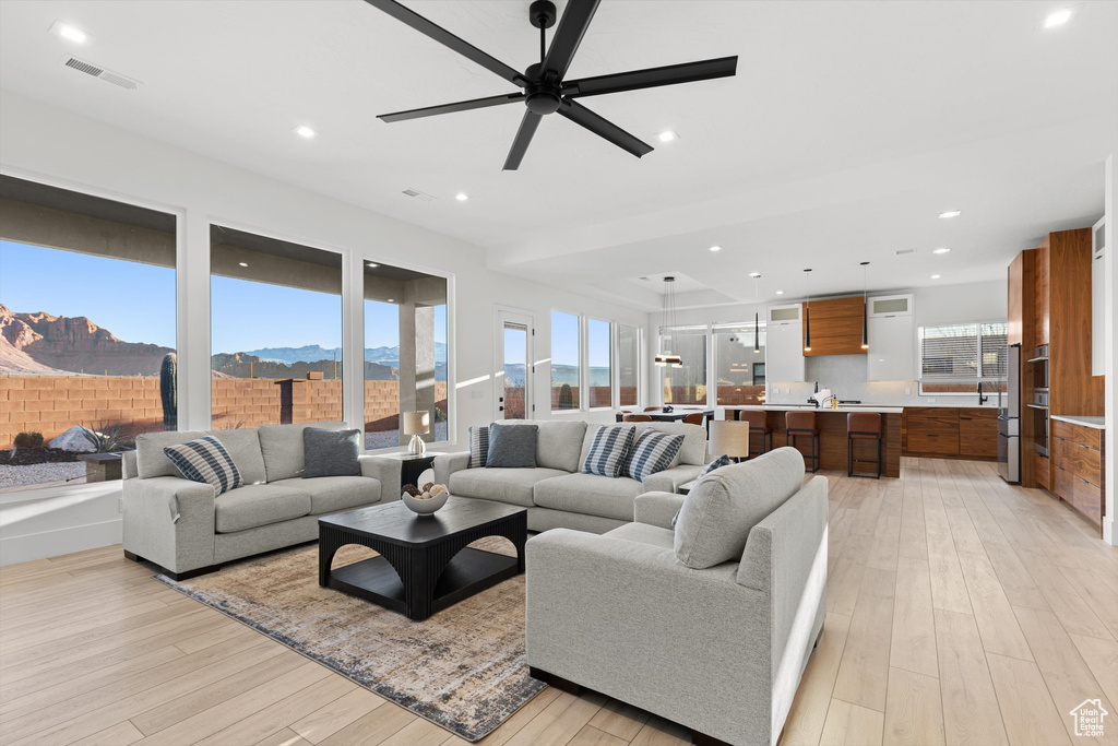 Living room featuring light wood finished floors, a ceiling fan, a mountain view, and recessed lighting