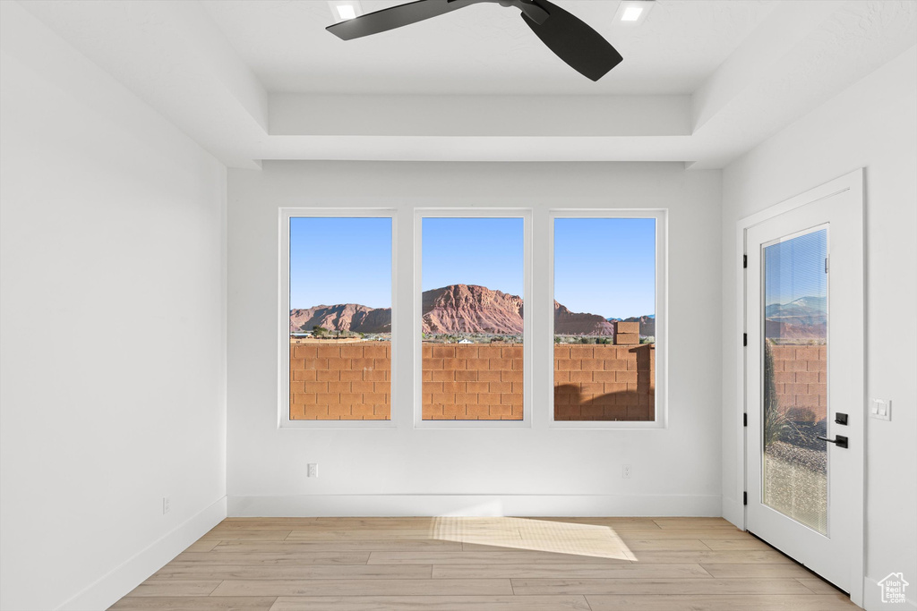 Unfurnished room featuring a tray ceiling, ceiling fan, and healthy amount of natural light