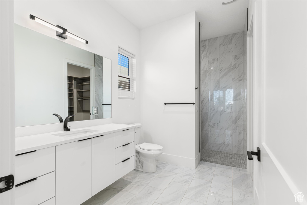 Full bathroom with marble finish flooring, a marble finish shower, vanity, toilet, and baseboards
