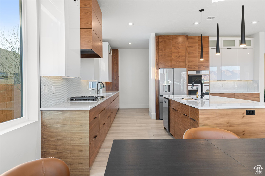 Kitchen with modern cabinets, custom range hood, light wood-style flooring, stainless steel appliances, and recessed lighting