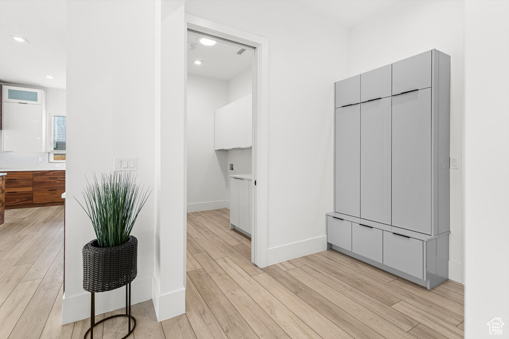 Hallway featuring light wood finished floors, baseboards, and recessed lighting