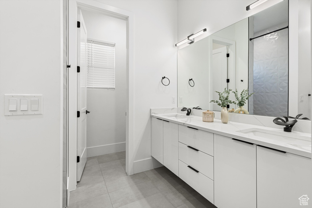 Bathroom featuring double vanity, tile patterned floors, and baseboards