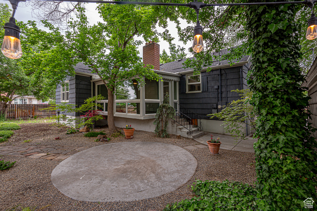 Back of property with a shingled roof, a chimney, fence, and a sunroom