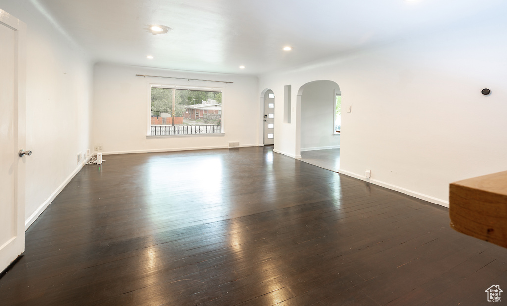 Unfurnished room with arched walkways, wood-type flooring, recessed lighting, and baseboards