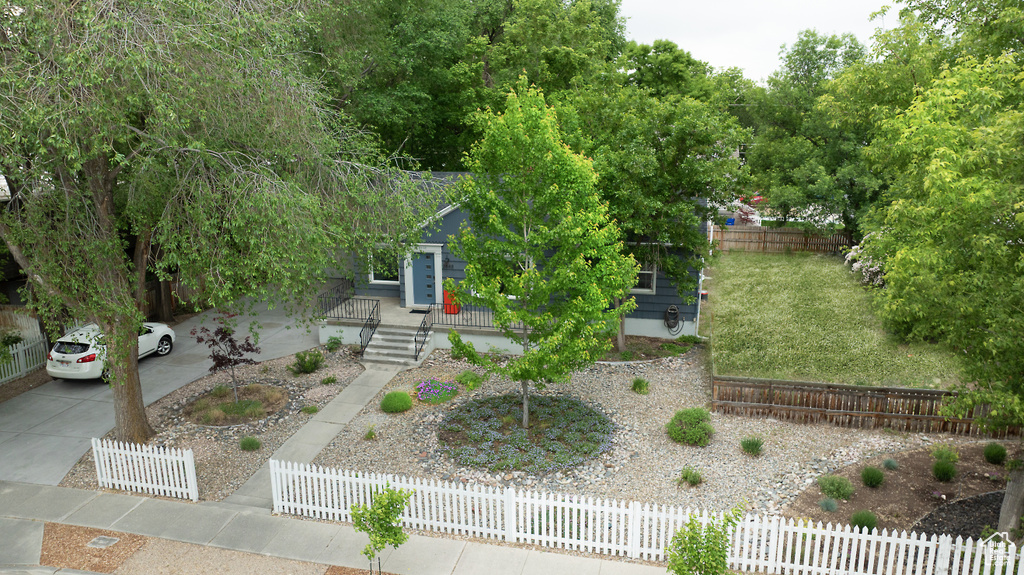 View of property hidden behind natural elements with a fenced front yard