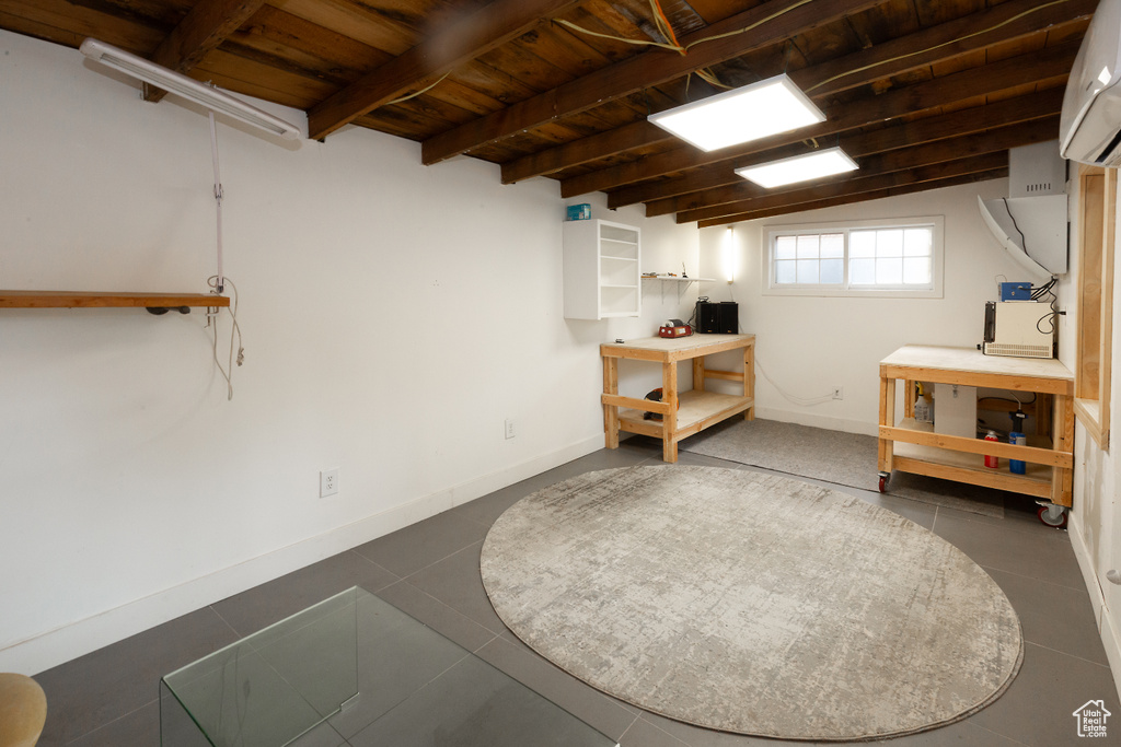 Basement featuring wood ceiling, an AC wall unit, tile patterned floors, and baseboards