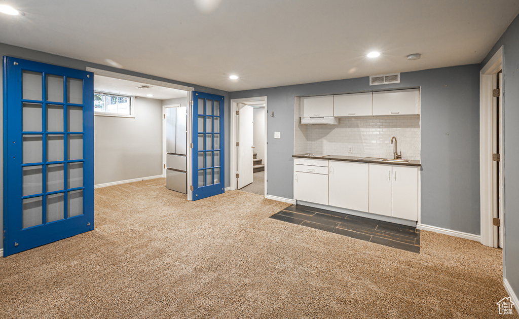 Kitchen featuring carpet floors, a sink, white cabinets, recessed lighting, and decorative backsplash
