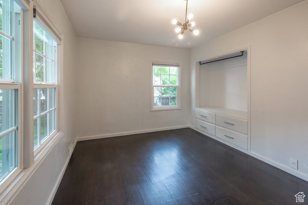 Unfurnished bedroom with multiple windows, dark wood-style floors, and baseboards