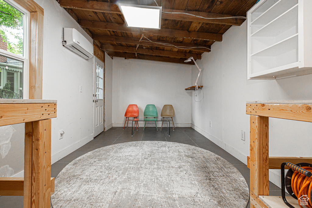 Below grade area featuring a wall mounted air conditioner, wooden ceiling, and baseboards