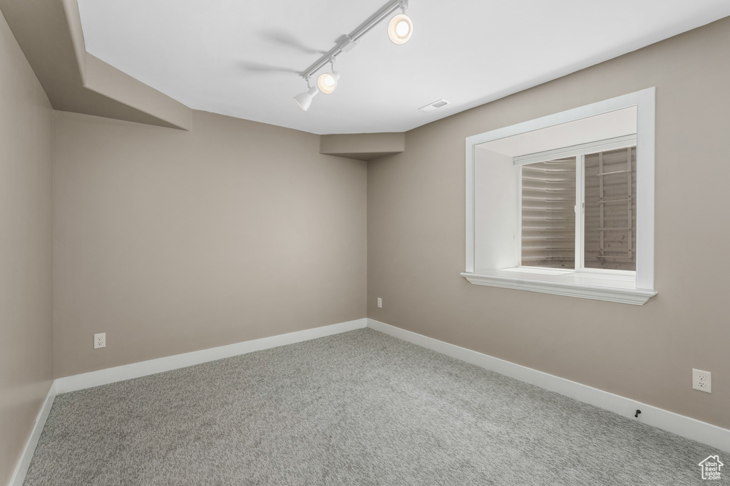 Unfurnished room with carpet flooring, baseboards, and track lighting