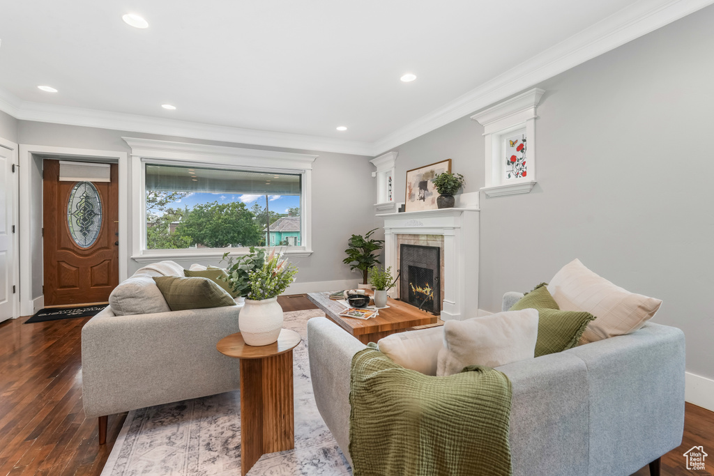 Living room featuring a tile fireplace, crown molding, recessed lighting, dark wood-style flooring, and baseboards
