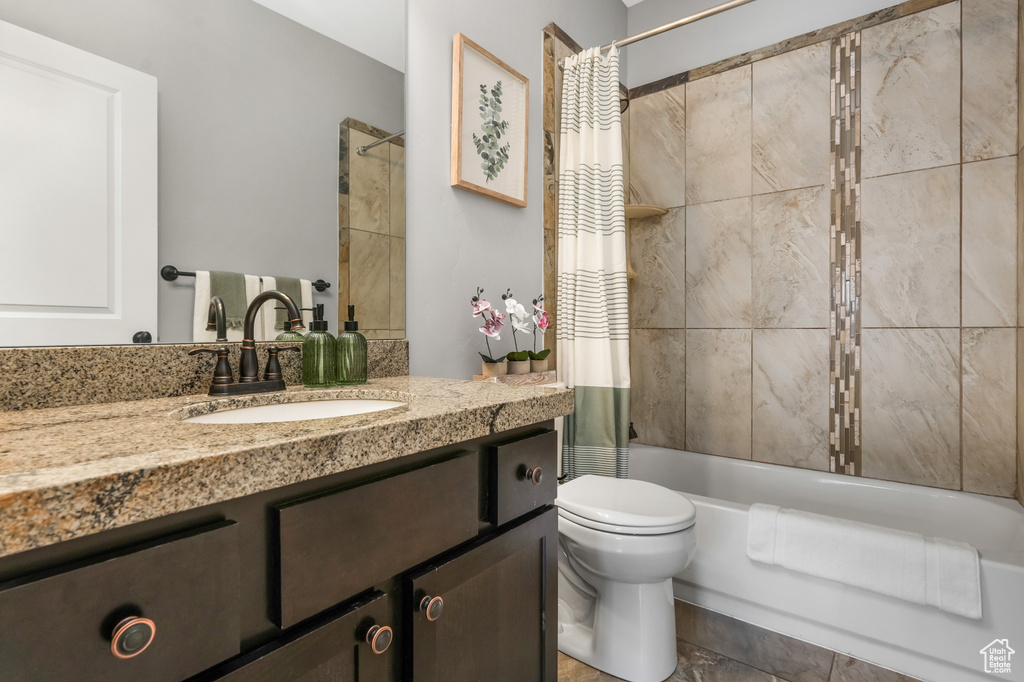 Bathroom featuring shower / bath combo with shower curtain, toilet, and vanity