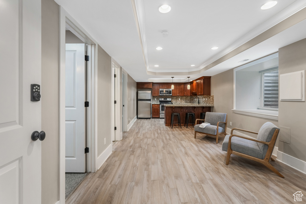 Living area featuring light wood finished floors, a raised ceiling, baseboards, and recessed lighting