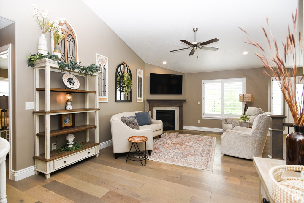 Living area with a ceiling fan, recessed lighting, light wood-type flooring, a fireplace, and baseboards