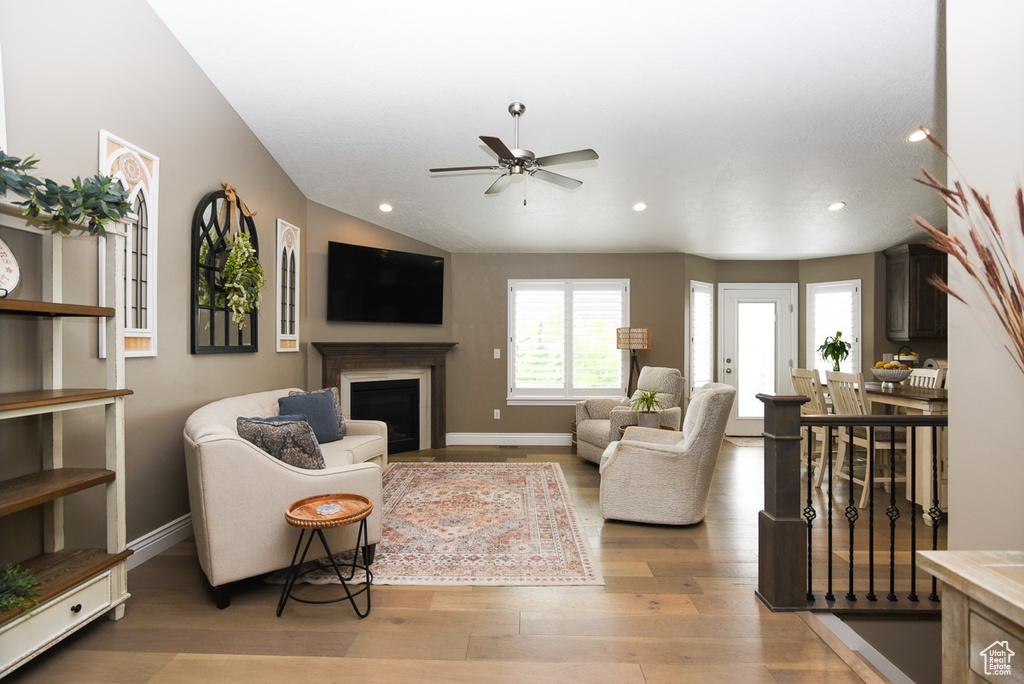 Living room featuring ceiling fan, light wood finished floors, a fireplace, recessed lighting, and baseboards