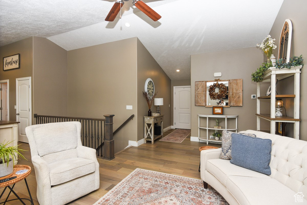 Living room featuring wood finished floors, a ceiling fan, baseboards, recessed lighting, and lofted ceiling
