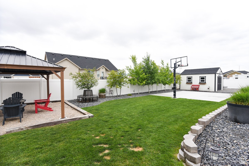 View of yard with a gazebo, a patio area, an outbuilding, and a fire pit