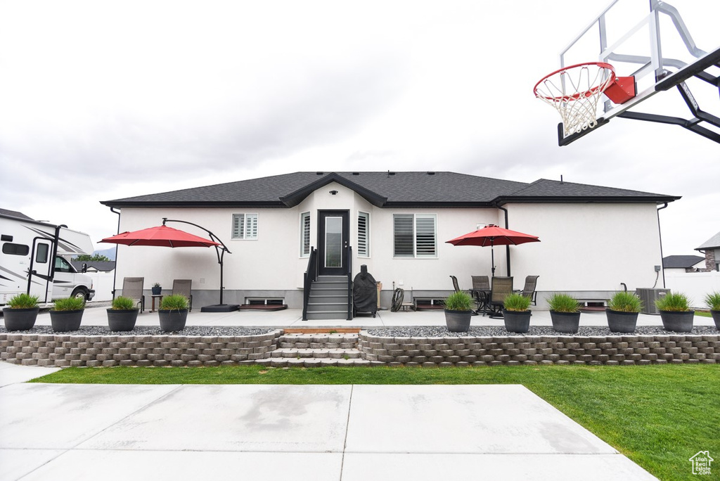 Rear view of house featuring stucco siding, entry steps, a patio area, and a yard