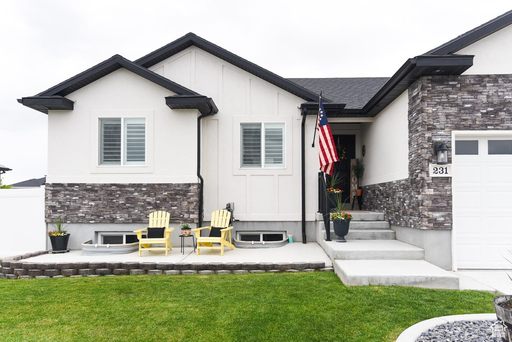View of exterior entry with stone siding, a lawn, and board and batten siding