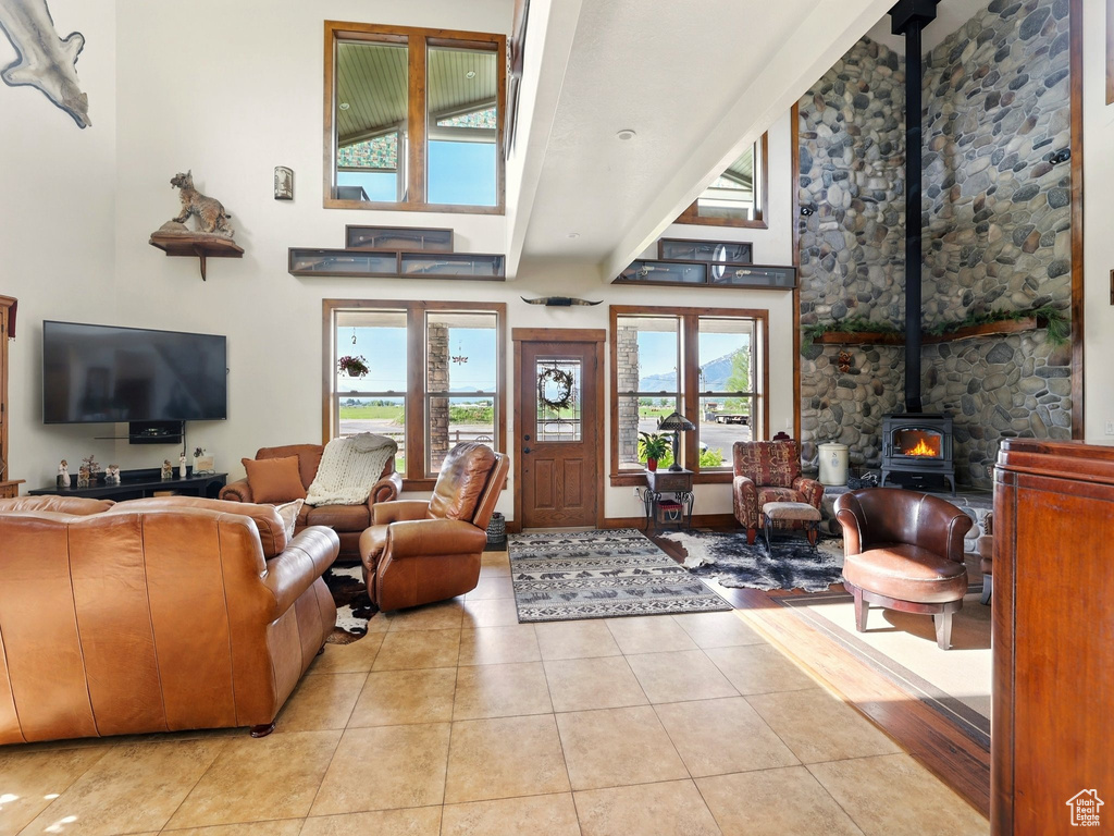 Living room featuring a wood stove, a towering ceiling, and tile patterned floors