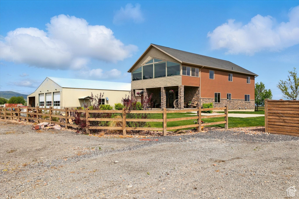 View of front of house with a fenced front yard, a sunroom, stone siding, and a detached garage