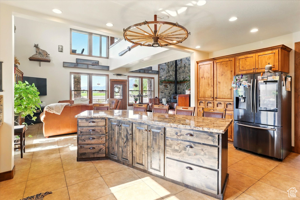 Kitchen with stainless steel fridge, recessed lighting, light stone counters, light tile patterned floors, and open floor plan