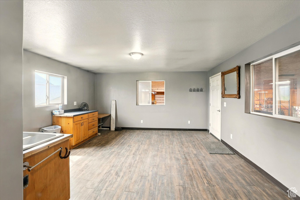 Kitchen featuring light wood-type flooring, light countertops, a sink, brown cabinetry, and baseboards