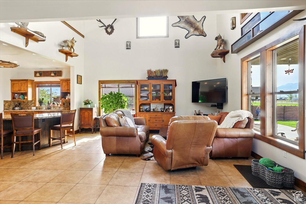 Living area with light tile patterned flooring, a high ceiling, and healthy amount of natural light