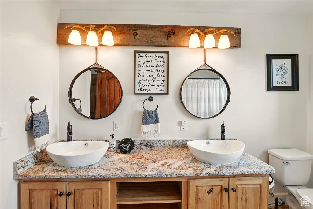 Full bathroom featuring toilet and double vanity