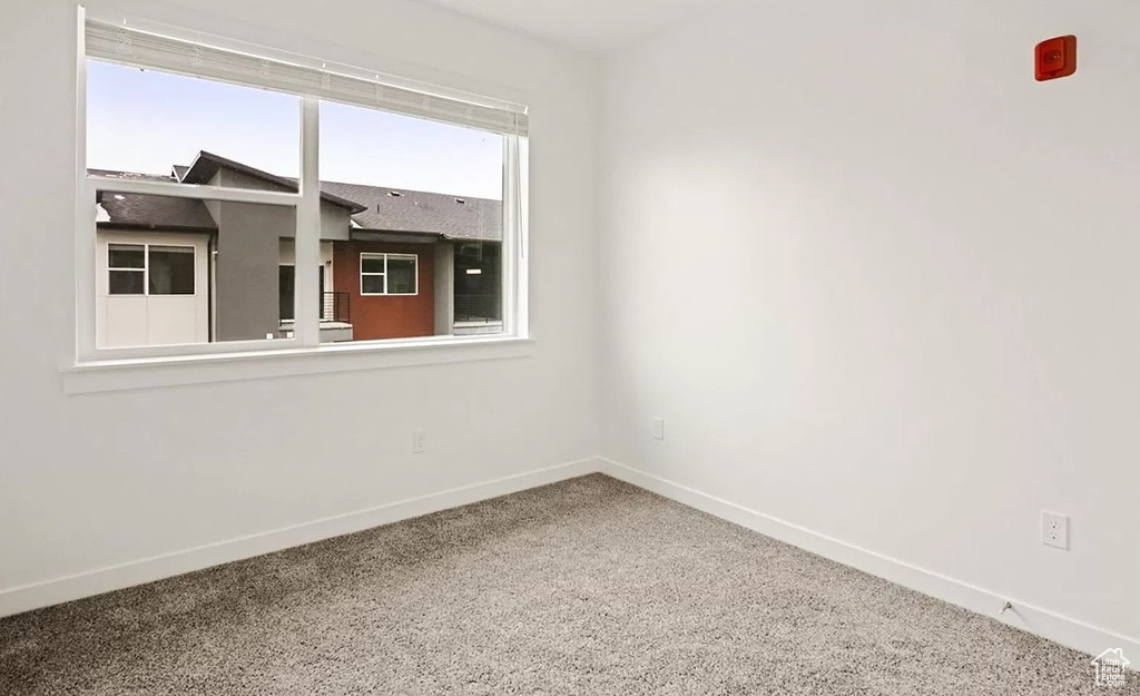 Carpeted spare room featuring baseboards