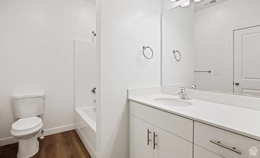 Bathroom with toilet, baseboards, visible vents, wood finished floors, and vanity