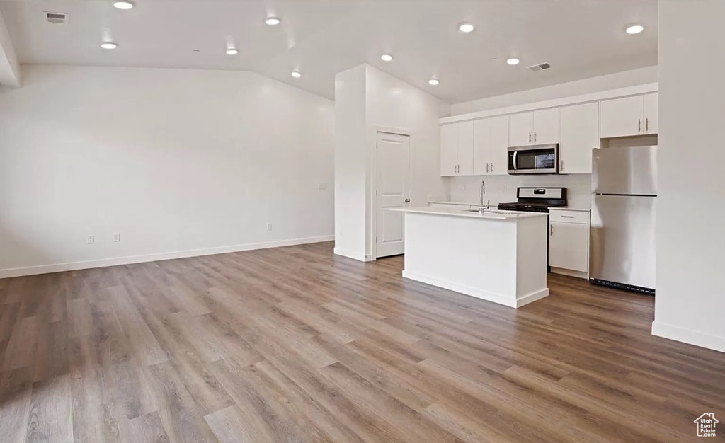 Kitchen featuring baseboards, recessed lighting, white cabinetry, an island with sink, and appliances with stainless steel finishes