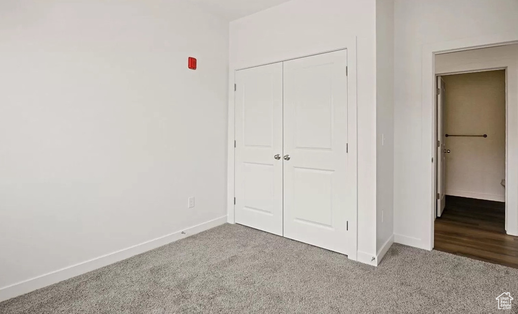 Unfurnished bedroom with baseboards, a closet, and carpet