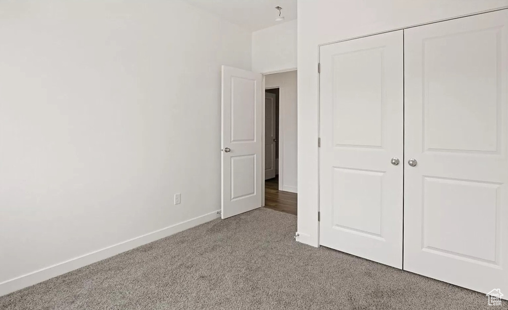 Unfurnished bedroom featuring baseboards, carpet flooring, and a closet