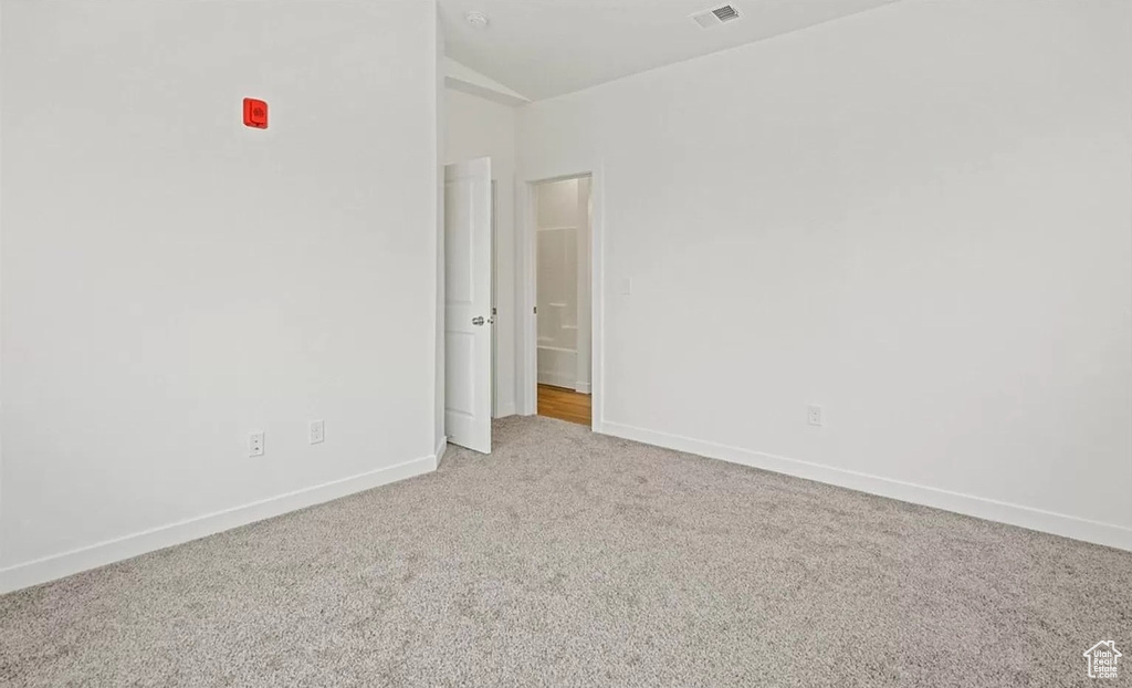 Carpeted spare room featuring lofted ceiling, baseboards, and visible vents