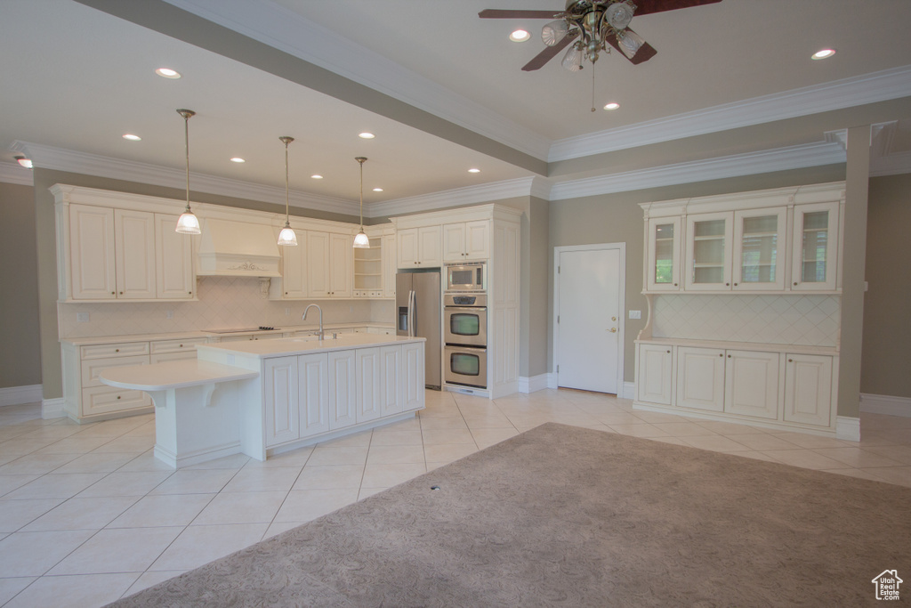 Kitchen with appliances with stainless steel finishes, light tile patterned flooring, a ceiling fan, light countertops, and crown molding