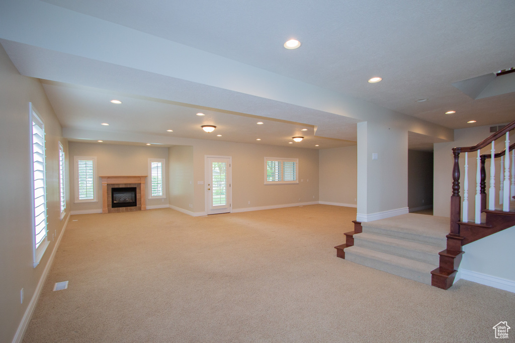 Unfurnished living room with light carpet, stairs, baseboards, recessed lighting, and healthy amount of natural light
