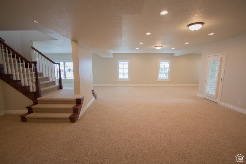 Basement with light carpet, stairs, baseboards, and recessed lighting