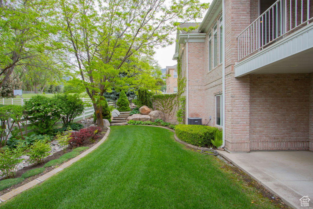 View of green lawn featuring a balcony and central AC