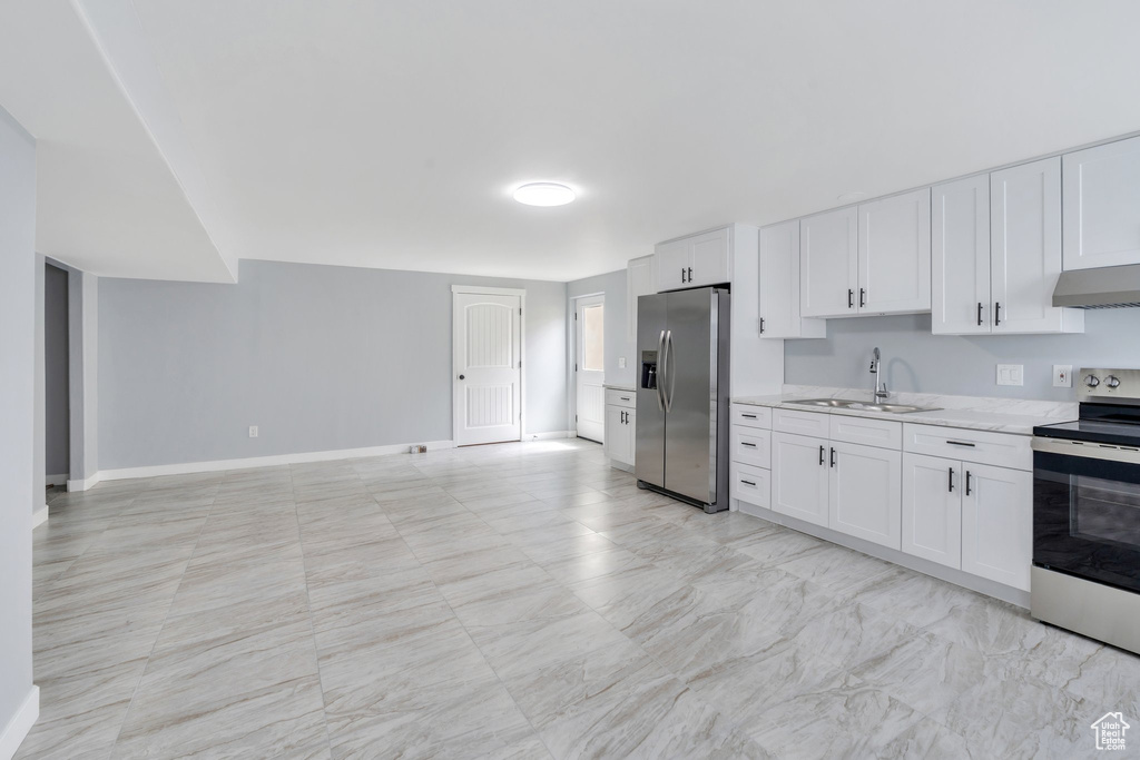 Kitchen featuring a sink, stainless steel appliances, under cabinet range hood, white cabinetry, and baseboards