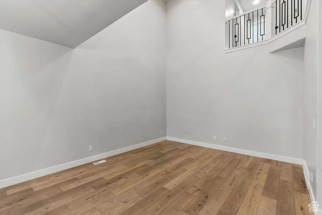 Bonus room with wood-type flooring, baseboards, and high vaulted ceiling